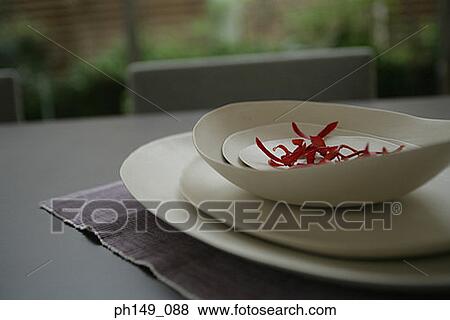 Stock Photo - Close-up of petals in a bowl over a stack of plates. Fotosearch