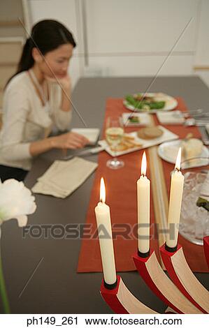 Close-up of three lit candles at the dining table with a young woman sitting in the background View Large Photo Image Stock Image - Close-up of three lit candles at the dining table with a young woman sitting in the background. Fotosearch