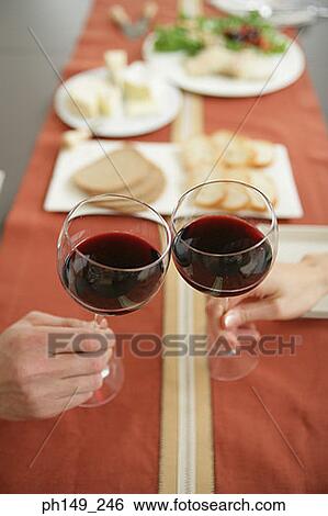 Close-up of two people toasting glasses of red wine View Large Photo Image Stock Photograph - Close-up of two people toasting glasses of red wine. Fotosearch