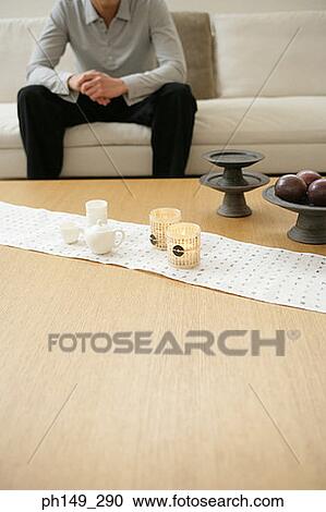 Stock Image - Cup and fruit on the table with a man sitting in the background. Fotosearch