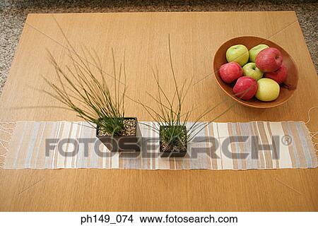 High angle view of a bowl of apples and two houseplants on the table View Large Photo Image Picture - High angle view of a bowl of apples and two houseplants on the table. Fotosearch