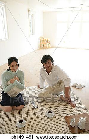High angle view of a young couple sitting on a mat and watching television View Large Photo Image Stock Image - High angle view of a young couple sitting on a mat and watching television. Fotosearch