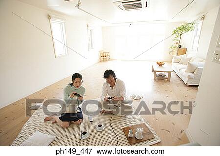 Stock Photo - High angle view of a young couple sitting on a mat and playing video games. Fotosearch