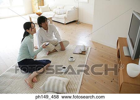 High angle view of a young couple sitting on a mat and watching television View Large Photo Image Stock Photo - High angle view of a young couple sitting on a mat and watching television. Fotosearch