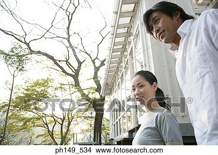 Picture - Low angle view of a young couple standing in front of a house. Fotosearch