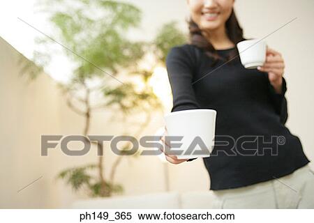 Low angle view of a young woman holding two coffee cups View Large Photo Image Stock Photography - Low angle view of a young woman holding two coffee cups. Fotosearch