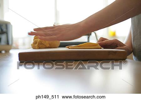 Stock Image - Mid section view of a woman preparing food in the kitchen. Fotosearch