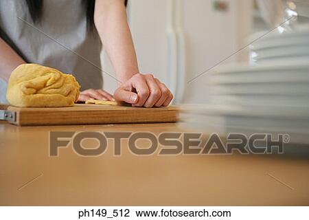 Stock Image - Mid section view of a woman preparing food in the kitchen. Fotosearch