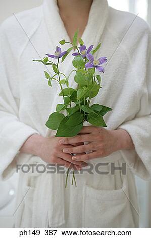 Stock Photo - Mid section view of a young woman holding flowers. Fotosearch