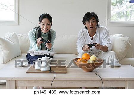 Portrait of a young couple sitting on a couch and playing video games View Large Photo Image Stock Photo - Portrait of a young couple sitting on a couch and playing video games. Fotosearch