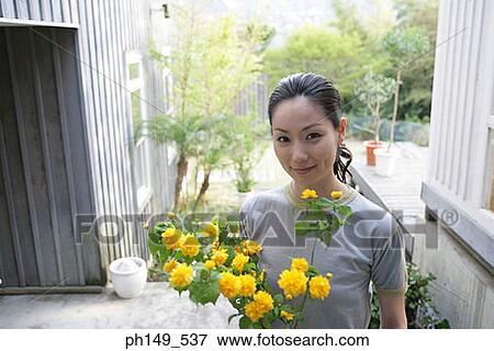Portrait of a young woman holding flowers View Large Photo Image Stock Photo - Portrait of a young woman holding flowers. Fotosearch
