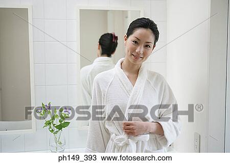 Stock Image - Portrait of a young woman standing in the bathroom and smiling. Fotosearch