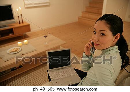 Portrait of a young woman talking on a mobile phone with a laptop on her lap View Large Photo Image Stock Photography - Portrait of a young woman talking on a mobile phone with a laptop on her lap. Fotosearch
