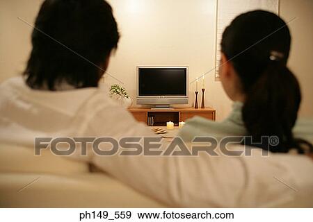 Stock Photo - Rear view of a young couple in front of a television. Fotosearch