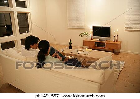 Rear view of a young couple sitting on a couch View Large Photo Image Stock Photo - Rear view of a young couple sitting on a couch. Fotosearch
