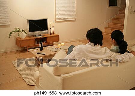Rear view of a young couple sitting on a couch View Large Photo Image Stock Photo - Rear view of a young couple sitting on a couch. Fotosearch