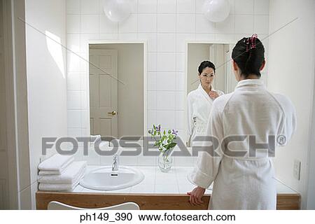 Rear view of a young woman in front of a mirror View Large Photo Image Stock Image - Rear view of a young woman in front of a mirror. Fotosearch