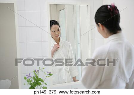 Stock Photo - Rear view of a young woman in front of a mirror. Fotosearch