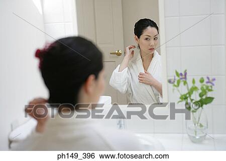 Rear view of a young woman in front of a mirror View Large Photo Image Stock Photograph - Rear view of a young woman in front of a mirror. Fotosearch