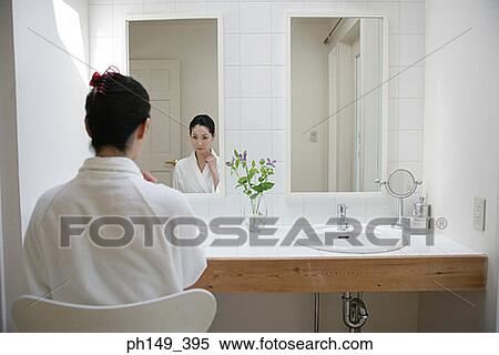 Rear view of a young woman in front of a mirror View Large Photo Image Stock Photography - Rear view of a young woman in front of a mirror. Fotosearch