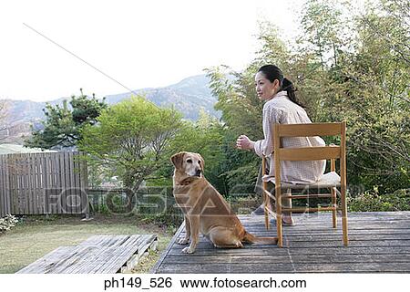 Rear view of a young woman sitting in an armchair with her pets View Large Photo Image Stock Photograph - Rear view of a young woman sitting in an armchair with her pets. Fotosearch