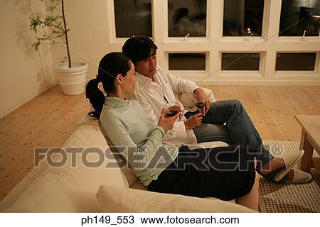 Side profile of a young couple holding wineglasses and sitting on a couch View Large Photo Image Stock Image - Side profile of a young couple holding wineglasses and sitting on a couch. Fotosearch