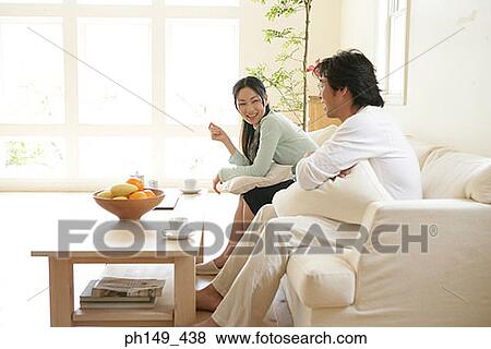 Side profile of a young couple sitting on a couch and smiling View Large Photo Image Stock Photo - Side profile of a young couple sitting on a couch and smiling. Fotosearch