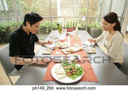 Side profile of a young couple sitting at the dining table View Large Photo Image Stock Photography - Side profile of a young couple sitting at the dining table. Fotosearch