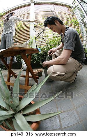 Stock Photography - Side profile of a young man holding a shovel with a young woman standing behind him. Fotosearch
