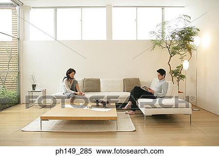 Side profile of a young man reading a magazine with a young woman sitting on a couch View Large Photo Image Stock Photography - Side profile of a young man reading a magazine with a young woman sitting on a couch. Fotosearch