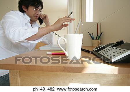 Side profile of a young man using a laptop and talking on the telephone View Large Photo Image Stock Image - Side profile of a young man using a laptop and talking on the telephone. Fotosearch