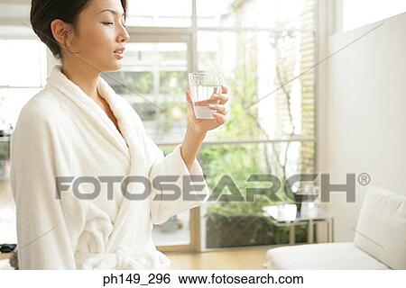 Side profile of a young woman holding a glass of water View Large Photo Image Stock Photograph - Side profile of a young woman holding a glass of water. Fotosearch