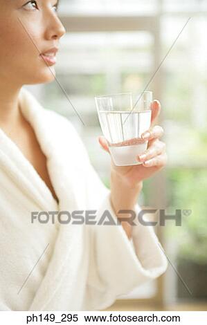 Side profile of a young woman holding a glass of water View Large Photo Image Stock Photography - Side profile of a young woman holding a glass of water. Fotosearch