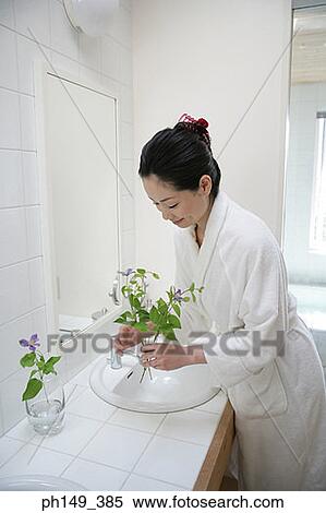 Side profile of a young woman putting flowers in a vase View Large Photo Image Stock Photography - Side profile of a young woman putting flowers in a vase. Fotosearch
