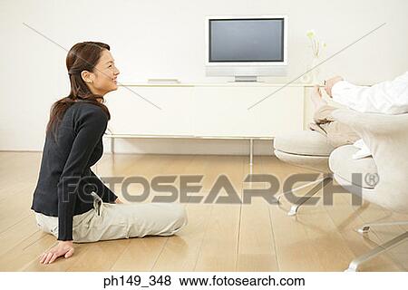 Side profile of a young woman sitting on the floor and looking at a man View Large Photo Image Stock Photo - Side profile of a young woman sitting on the floor and looking at a man. Fotosearch