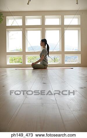 Stock Image - Side profile of a young woman practicing yoga. Fotosearch