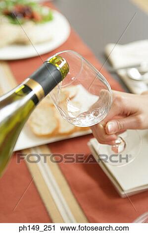 Stock Image - Wine being poured into a wine glass. Fotosearch