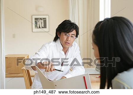 Young couple discussing a file View Large Photo Image Stock Photo - Young couple discussing a file. Fotosearch