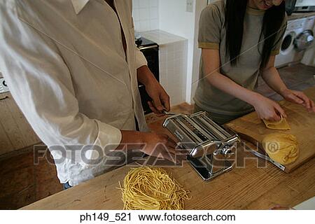 Young couple making noodles with the help of a pasta maker View Large Photo Image Stock Image - Young couple making noodles with the help of a pasta maker. Fotosearch