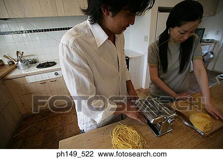 Young couple making noodles with the help of a pasta maker View Large Photo Image Stock Image - Young couple making noodles with the help of a pasta maker. Fotosearch