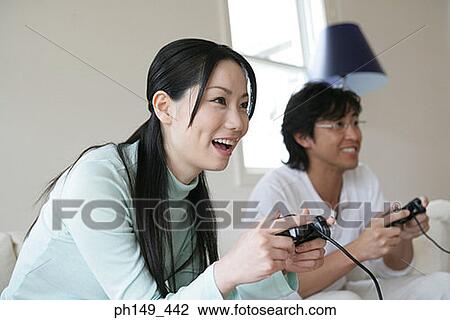Young couple playing a video game and smiling View Large Photo Image Stock Image - Young couple playing a video game and smiling. Fotosearch