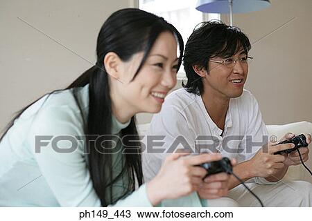 Young couple playing a video game and smiling View Large Photo Image Stock Image - Young couple playing a video game and smiling. Fotosearch