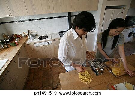 Young couple preparing food in the kitchen View Large Photo Image Stock Photo - Young couple preparing food in the kitchen. Fotosearch