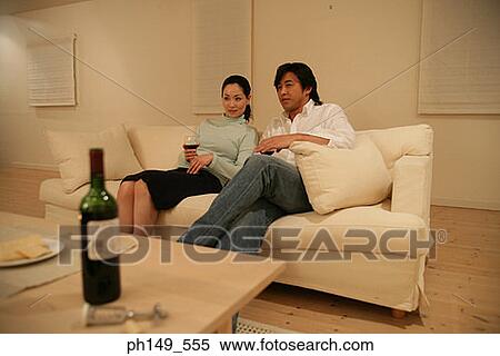 Young couple sitting on a couch and holding wineglasses View Large Photo Image Stock Photography - Young couple sitting on a couch and holding wineglasses. Fotosearch