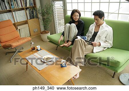 Young couple sitting on a couch View Large Photo Image Stock Image - Young couple sitting on a couch. Fotosearch