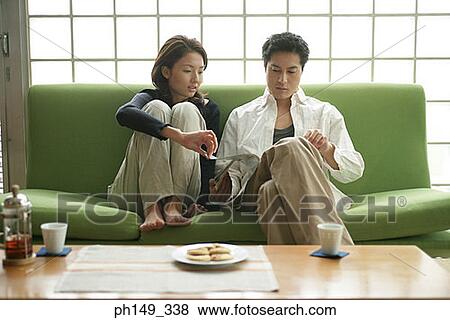 Young couple sitting on a couch View Large Photo Image Stock Photo - Young couple sitting on a couch. Fotosearch