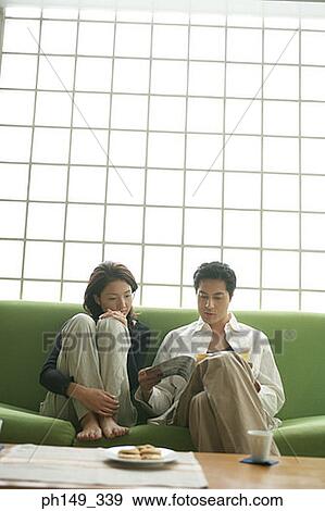 Stock Photo - Young couple sitting on a couch. Fotosearch
