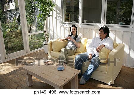 Young couple sitting on a couch View Large Photo Image Stock Photograph - Young couple sitting on a couch. Fotosearch
