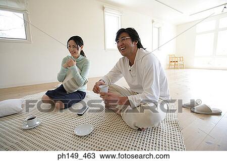 Young couple sitting on a mat and watching television View Large Photo Image Stock Image - Young couple sitting on a mat and watching television. Fotosearch