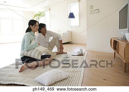 Young couple sitting on a mat and watching television View Large Photo Image Stock Photo - Young couple sitting on a mat and watching television. Fotosearch